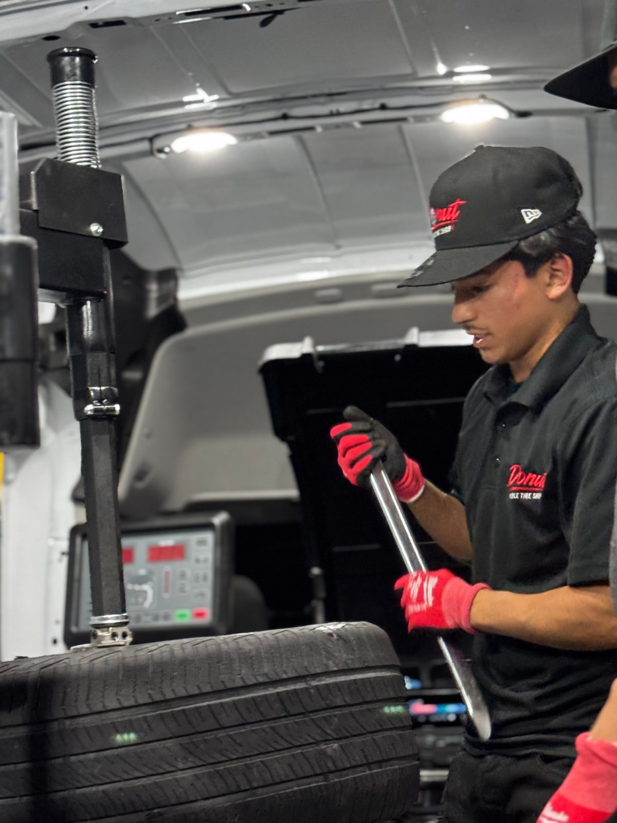 Donut Mobile Tire technician mounting a tire on the tire machine inside the service van